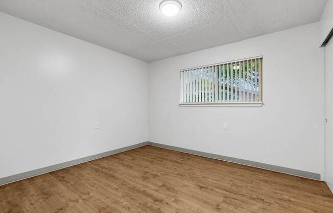 A room with a window and wooden flooring.