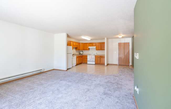 A room with a carpeted floor and a door leading to another room. Fargo, ND Stonebridge Apartments