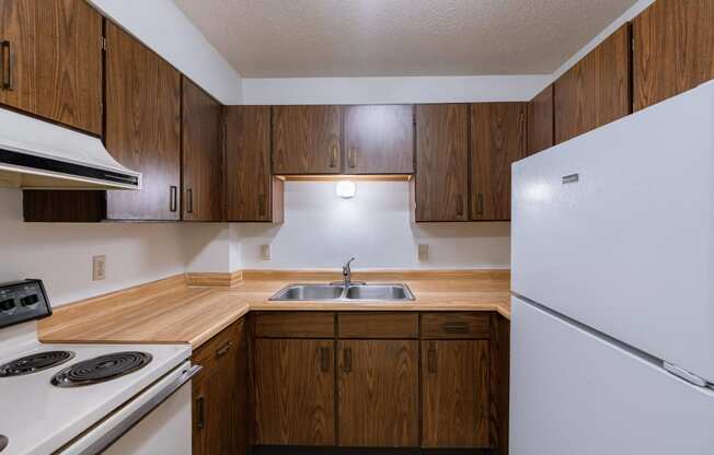 an empty kitchen with white appliances and wooden cabinets. Moorhead, MN South Park Apartments