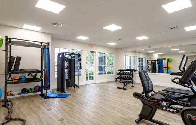 A gym with a variety of equipment including treadmills, weights, and exercise machines.