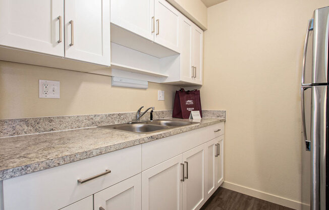 a kitchen with white cabinets and a sink and a refrigerator at Old Farm Apartments, Elkhart, Indiana