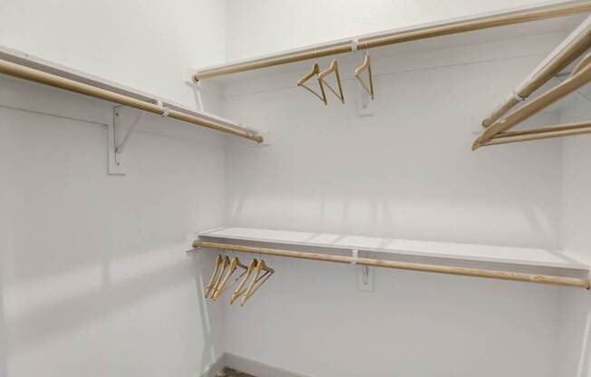 A white closet with two shelves and hangers at Infinity on the Point Apartments, Texas
