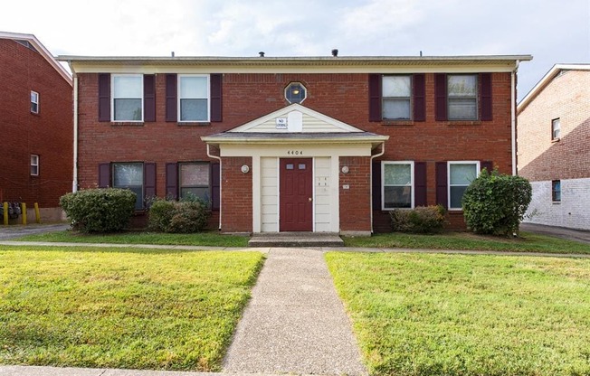 a red brick house with a sidewalk in front of it