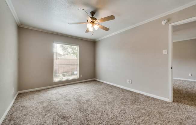 A room with a ceiling fan and carpeted floor.
