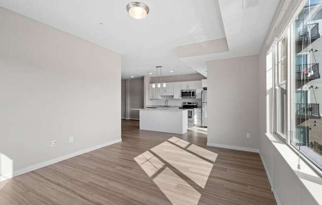 A spacious kitchen and living room with wooden flooring and white walls.