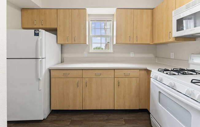 A kitchen with window, wooden cabinets and white appliancesat Stoney Pointe Apartment Homes, Kansas