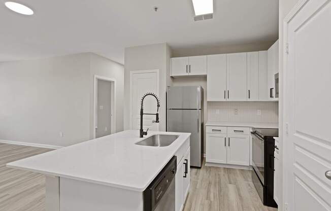 Flatiron West Trade Apartments staged model unit kitchen connected to living room with stainless steel modern appliances and quartz countertops