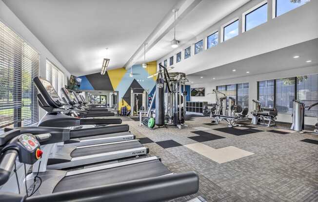 a gym with cardio equipment and weights in a building with windows  at Sunset Ridge, San Antonio, TX, 78209