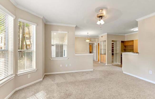 A spacious living room with a carpeted floor and a ceiling fan.