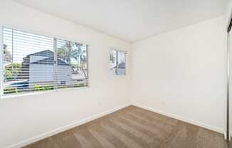 an empty bedroom with a large window and carpeted flooring