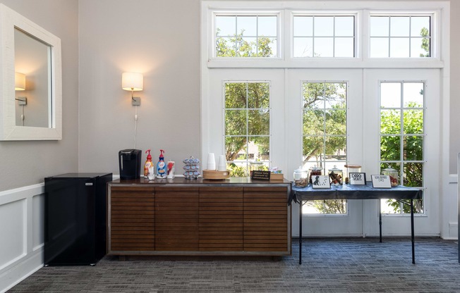 a bar in a room with large windows and a table with drinks on it