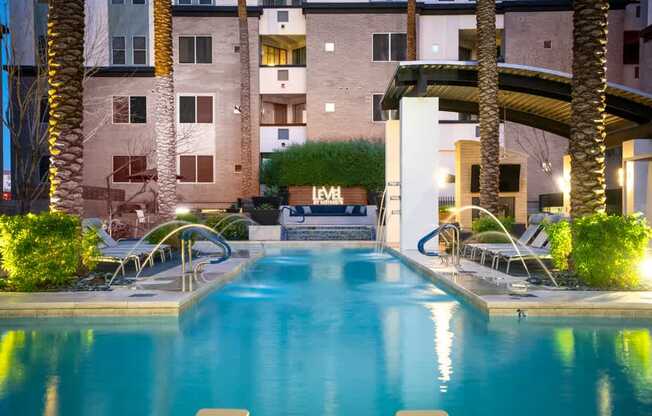 A swimming pool in front of a building with palm trees.