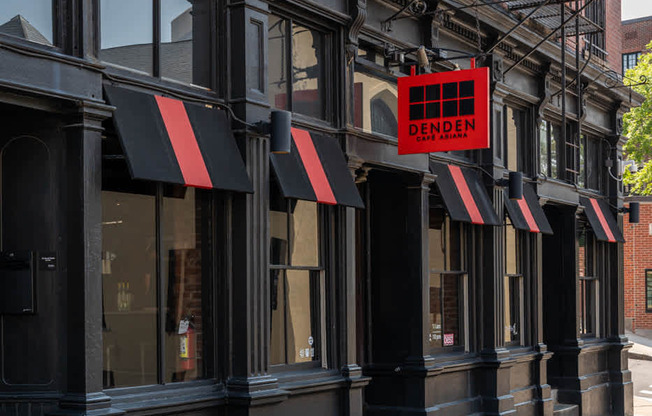 A black building with a red sign that says DENDEN cafe