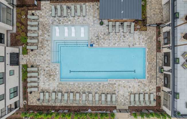 A swimming pool surrounded by a stone wall and lounge chairs.