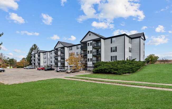 Apartment complex with a parking lot in front.
