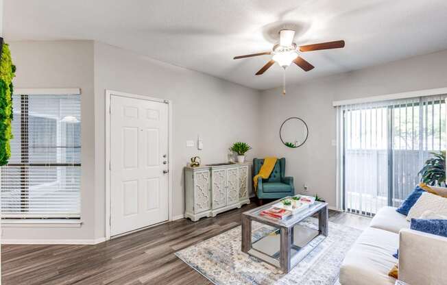 A living room with a white ceiling fan and a glass coffee table.