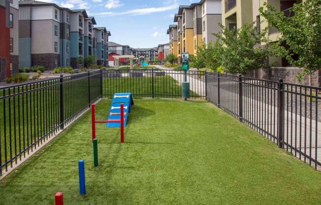 a grassy area with benches and a fence in front of an apartment complex