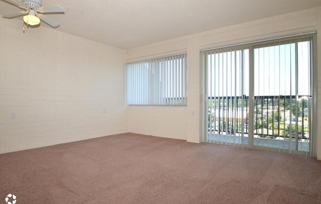 an empty living room with windows and a ceiling fan