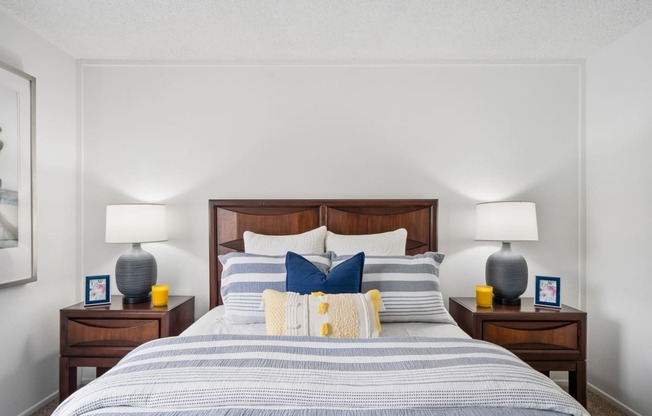 a bedroom with a bed with blue and white pillows and a wooden headboard