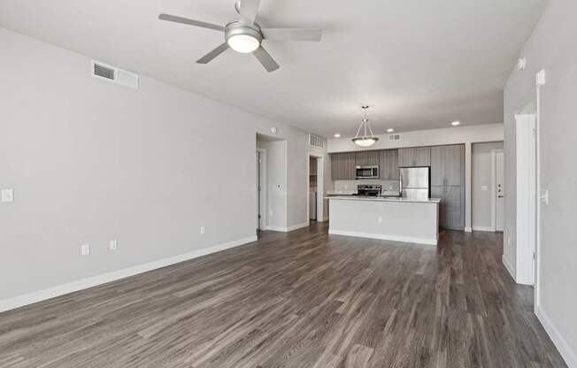 A room with a ceiling fan and wooden flooring.