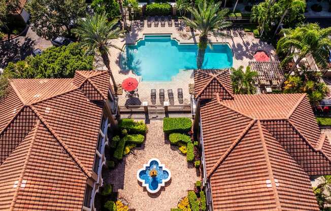 Aerial view of apartments near clubhouse with pool and landscaped greenery