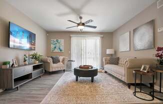 A living room with a flat screen TV mounted on the wall and a ceiling fan.